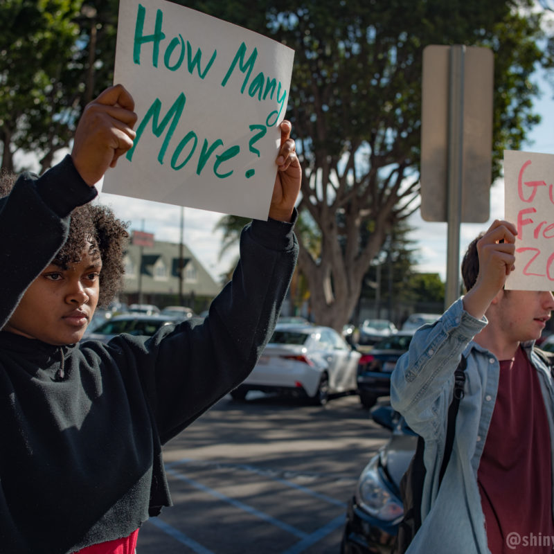 Young people hold up signs at rally against gun violence.