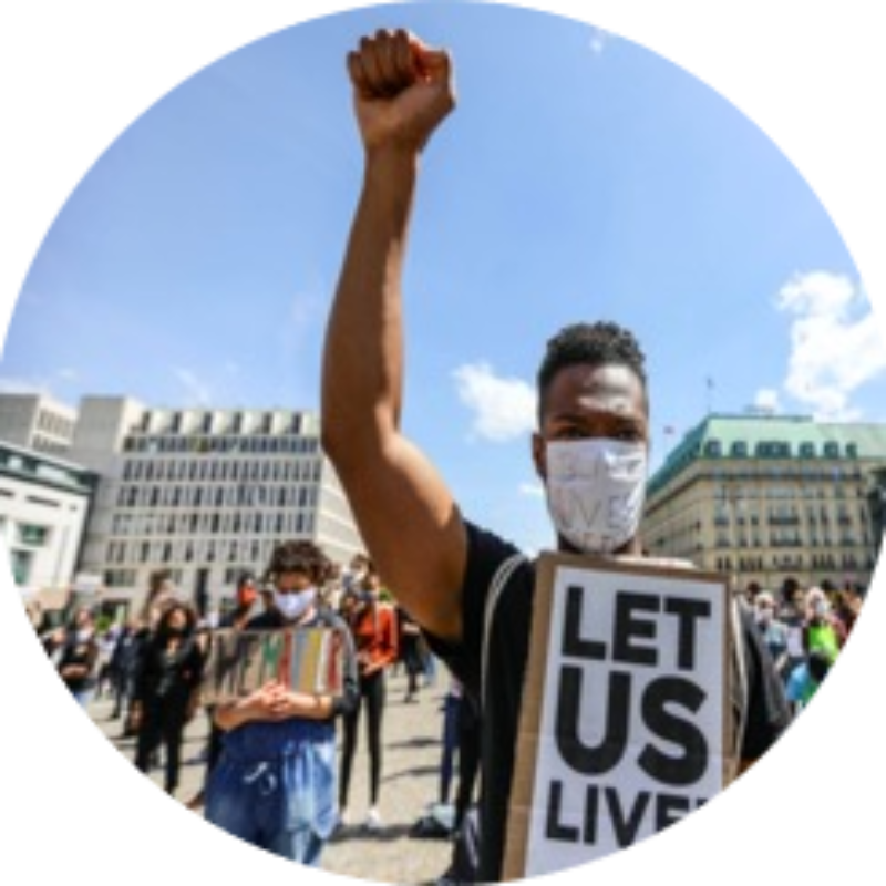 Man holds hand in the air, holding "Let Us Live" sign