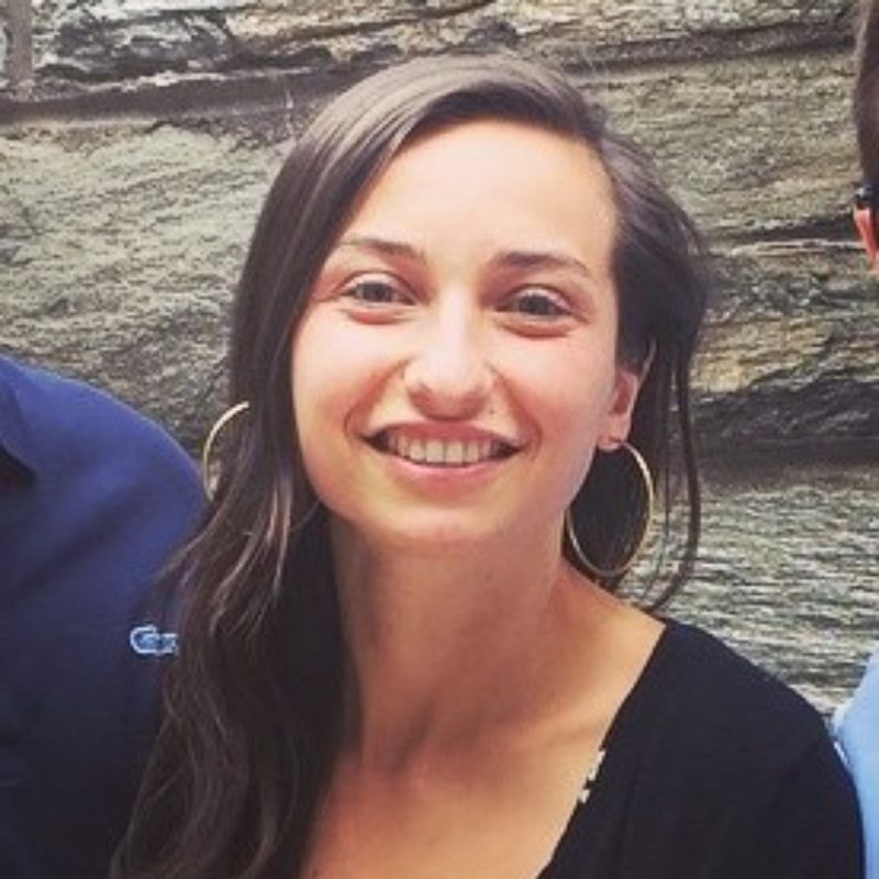 Woman smiles at camera in front of wall.