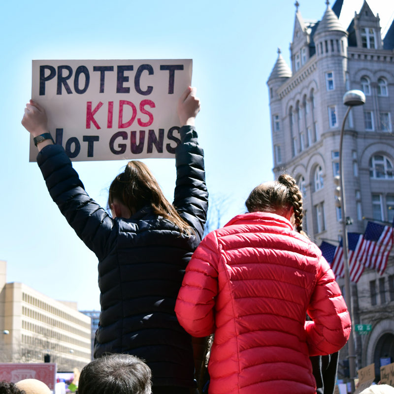 Woman holds sign that says, Protect Kids Not Guns