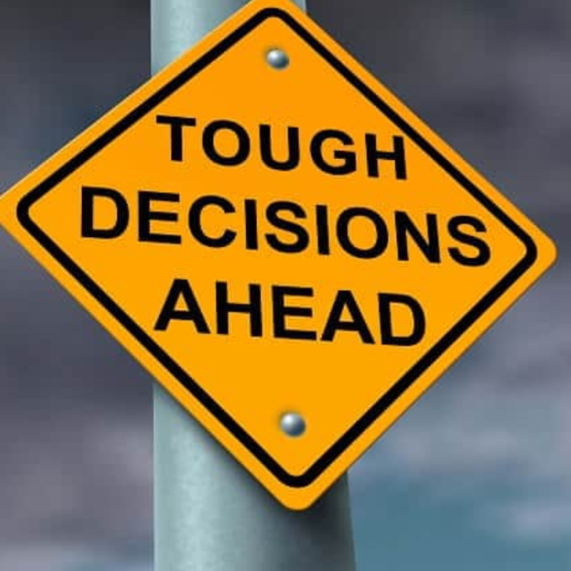 Sign reading Tough Decisions Ahead