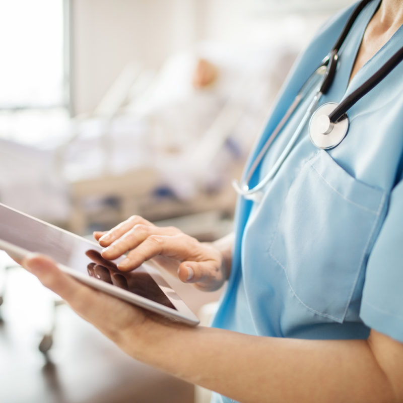 Female doctor reads news on an iPad.