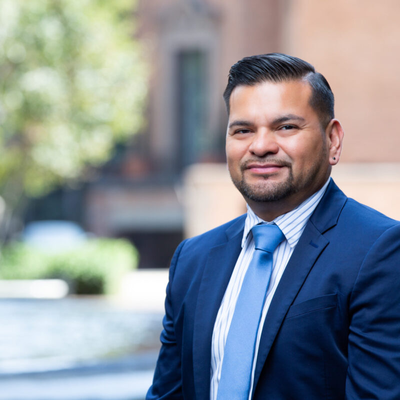 Man in suit in outdoor setting smiles at camera