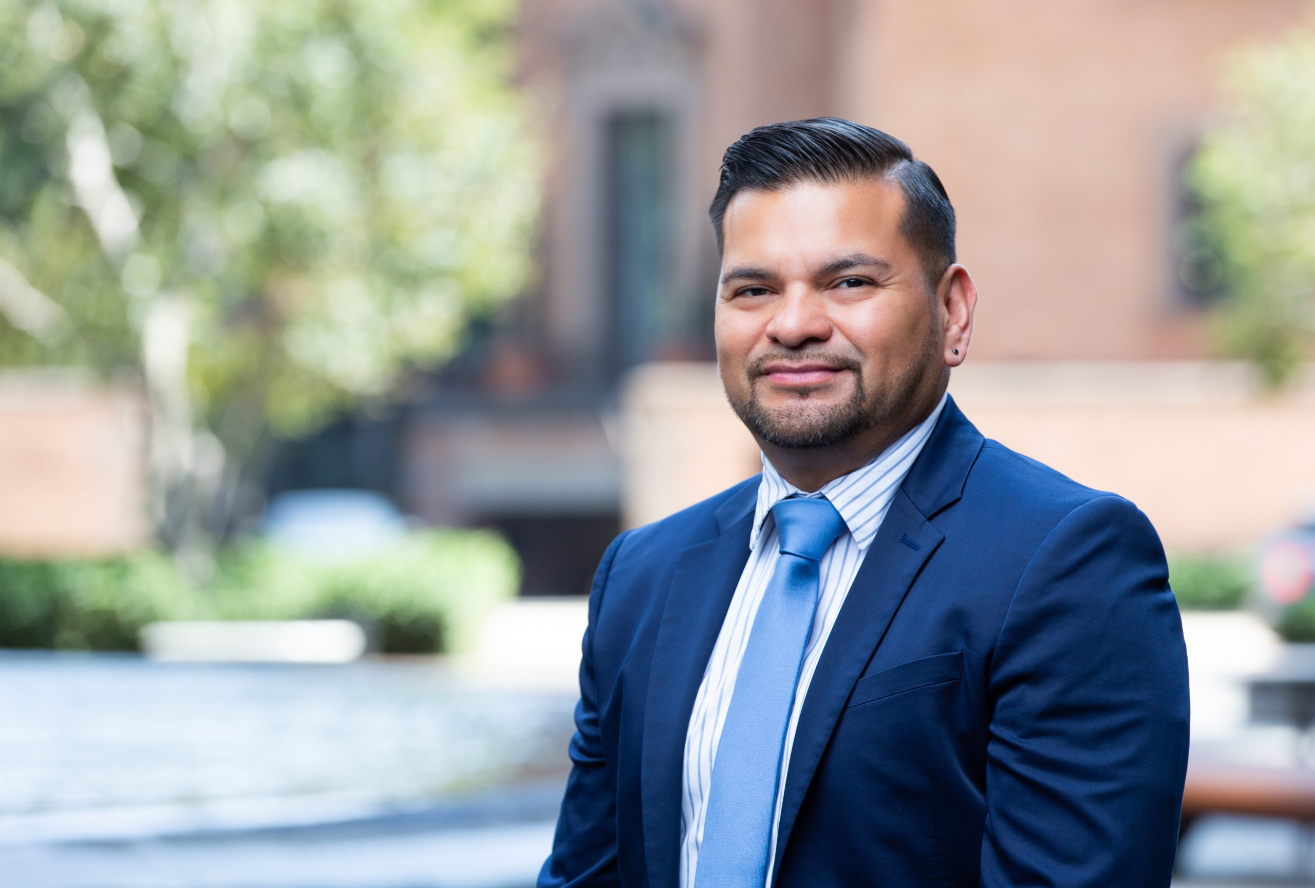 Man in suit in outdoor setting smiles at camera